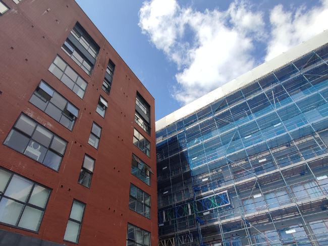 2 buildings one with scaffolding blue sky